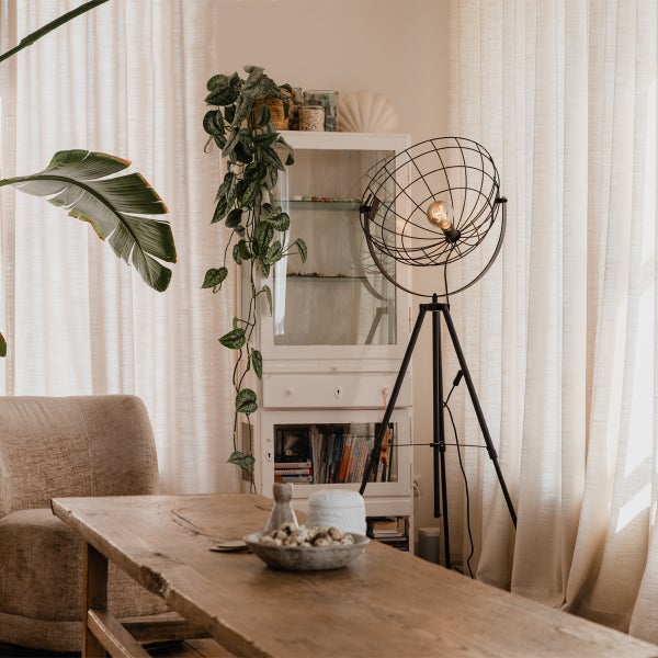 Wohnzimmer mit Holzmöbeln, Stehlampe und Zimmerpflanzen