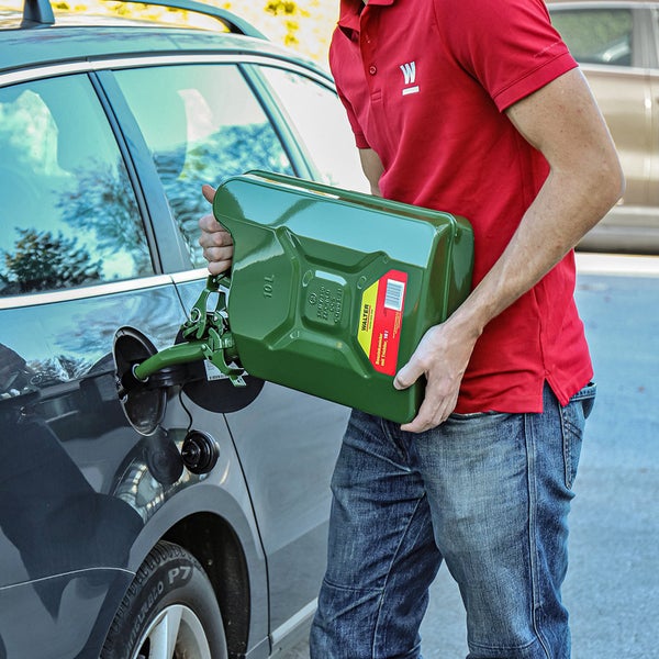 Eine Person füllt mit einem grünen 10 Liter Kraftstoffkanister Benzin in ein Auto.