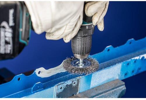 Drahtbürstenaufsatz für Bohrmaschine im Einsatz zum Entrosten von Metall.