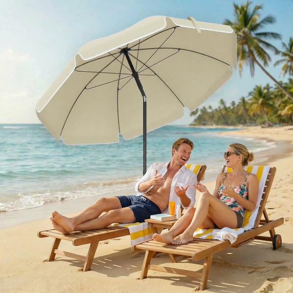 Beigefarbener Sonnenschirm mit Wellenrand spendet Schatten für zwei Personen in Liegestühlen am Strand.