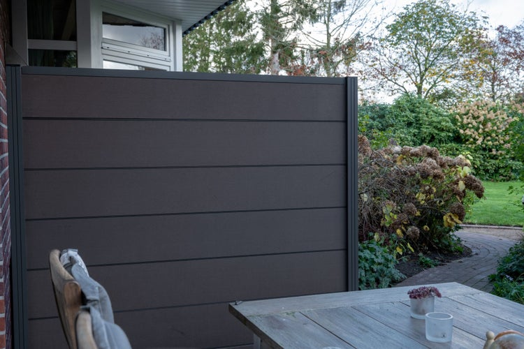 Sichtschutzzaun im Gartenbereich mit Holztisch und Stuhl