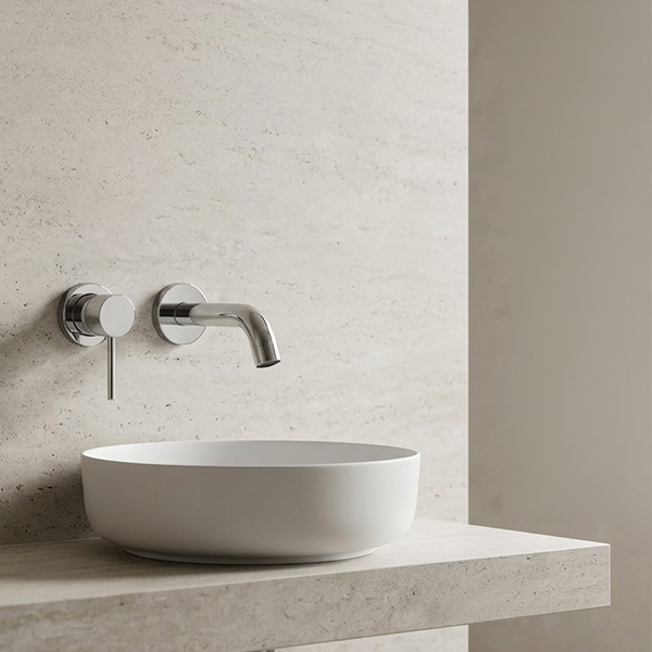 Helles, modernes Badezimmer mit weißem Aufsatzwaschbecken und verchromter Wandarmatur vor einer Wand in Steinoptik.