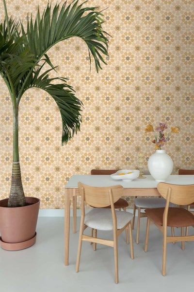 Tapete mit geometrischem Fliesenmuster in einem hellen Esszimmer mit Holztisch, Stühlen und einer großen Zimmerpflanze.