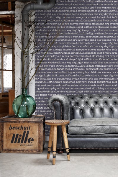 Wohnzimmer mit graublauem Sofa, Holzhocker, Holzkiste und Dekoration