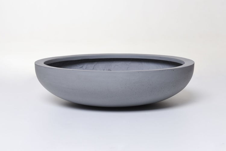 Runde, flache Pflanzschale in Betonoptik aus grauem Material.