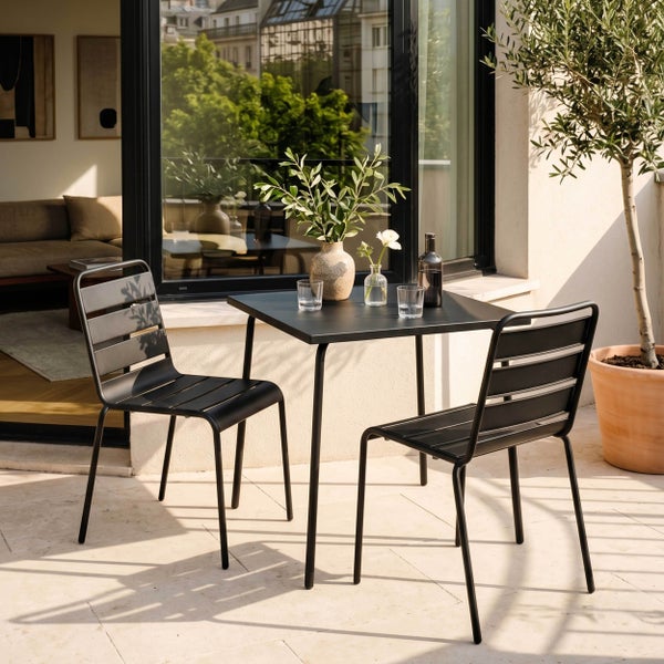 Modernes, schlichtes Balkonset aus schwarzem Metall mit quadratischem Tisch und zwei Lattenstühlen auf einer sonnigen Terrasse.