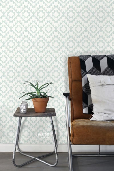 Zimmeransicht mit gemusterter Tapete, Pflanze auf Beistelltisch und Sessel