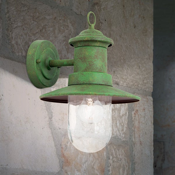 Klassische Außenwandleuchte aus grün patiniertem Metall mit klarem Glas an einer Steinwand.
