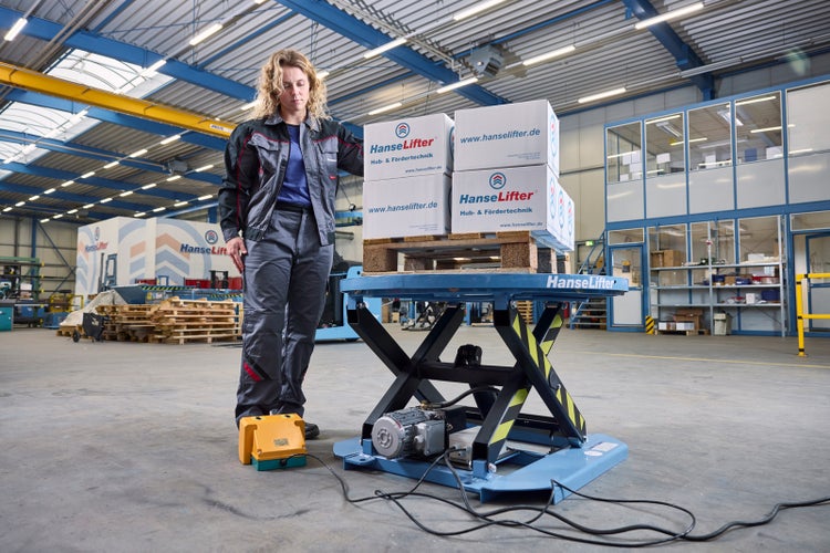 Stationärer Hubtisch von HanseLifter mit Fußpedal Steuerung und Palette in einer Industriehalle.