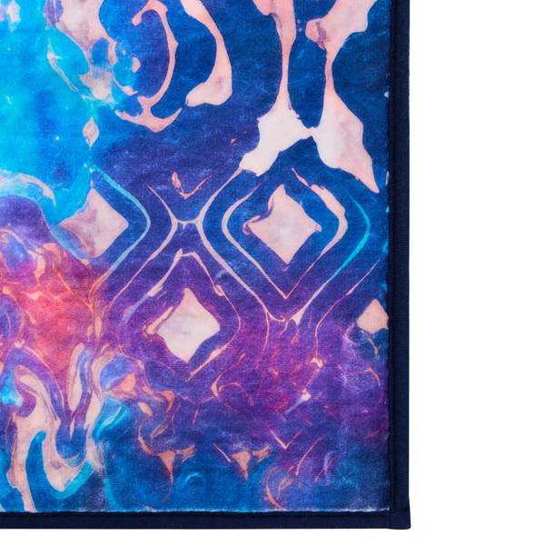 Nahaufnahme einer Teppichecke mit abstraktem Marmormuster und geometrischen Rauten in Blau und Violett.