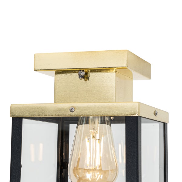 Detail einer Deckenleuchte im Laternen-Stil aus gold- und schwarzfarbenem Metall mit Glaseinsätzen und LED-Leuchtmittel.