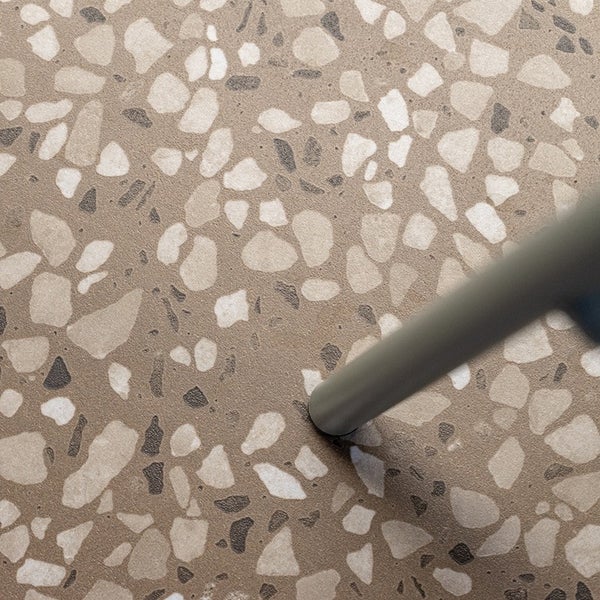 Fliese in Terrazzo Optik mit feiner Oberflächenstruktur und einem Möbelbein im Vordergrund