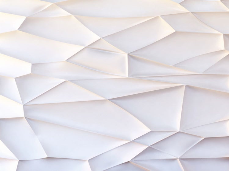 Schlafzimmer mit Bett, Nachttischen und dekorativen Elementen vor einer geometrischen Wand