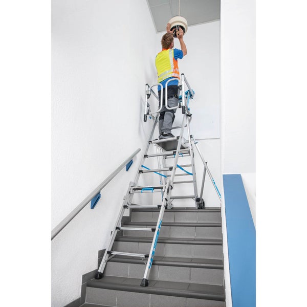 Eine Person montiert eine Lampe von einer Treppenleiter aus.