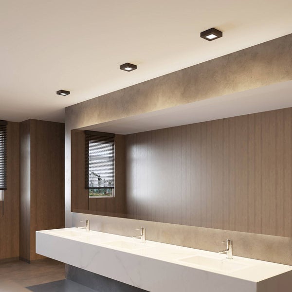 Modernes, helles Badezimmer mit langem weißem Waschtisch, drei Armaturen, großem Spiegel und quadratischen Deckenstrahlern.