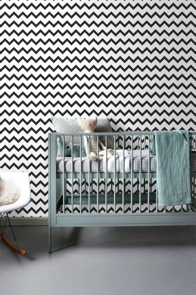 Kinderzimmer mit Zickzacktapete, Babybett und Schaukelstuhl