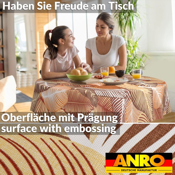 Runde Wachstuch-Tischdecke mit Blättermuster und geprägter Oberfläche auf einem gedeckten Esstisch in einem hellen Raum. ANRO Logo.