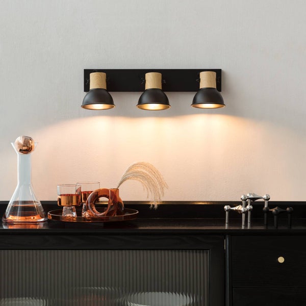 Wandleuchte mit drei Strahlern über einer Kommode im Interieur.