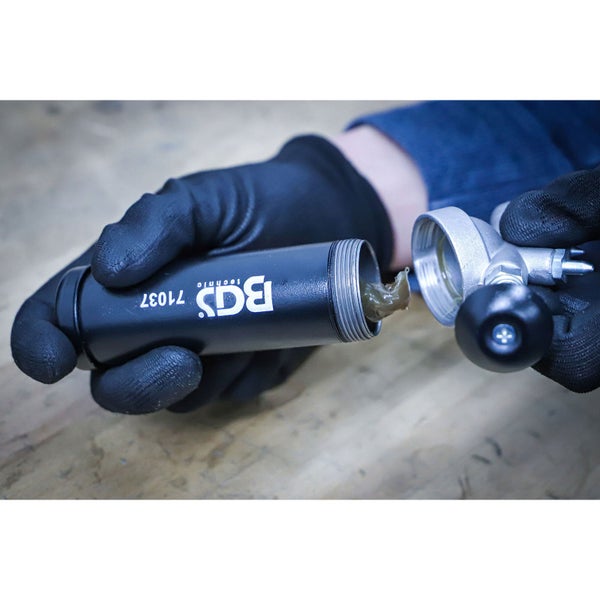 Hände in Handschuhen halten eine geöffnete BGS Technic Fettpresse mit Schmierfett.