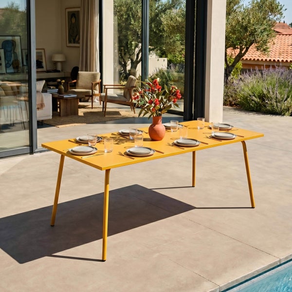 Moderner gelber Gartentisch auf einer hellen Terrasse am Pool, gedeckt für sechs Personen mit Geschirr und einer Blumenvase.