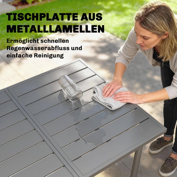 Modernes Gartenmöbel-Set mit großem rechteckigem Esstisch und sechs Stühlen auf einer Holzterrasse mit Blumen und Zaun im Hintergrund.