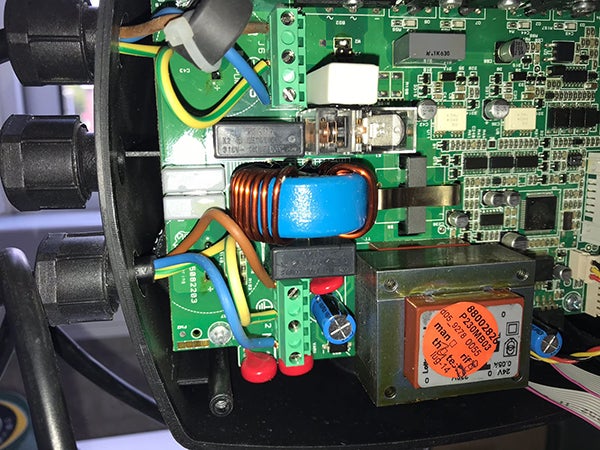 Nahaufnahme einer grünen Leiterplatte mit elektronischen Komponenten, Transformator, Induktivität und Verkabelung in einem Gehäuse.