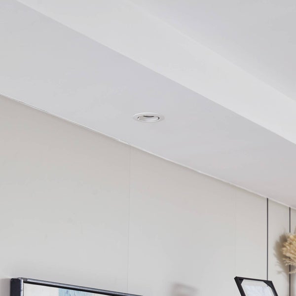 Moderner runder Einbaustrahler in einer Deckenkonstruktion über einer Wand in einem hellen Raum.