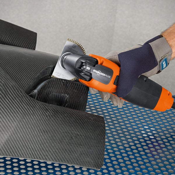 Eine Hand mit Handschuh bedient ein oszillierendes Multifunktionswerkzeug mit Starlock Plus Aufnahme.