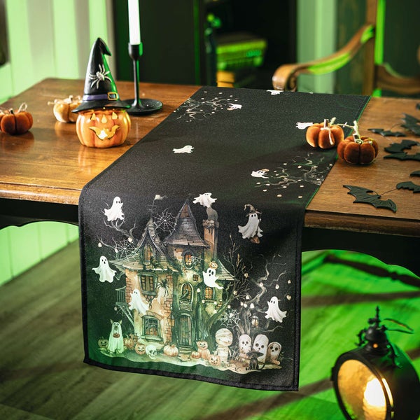 Dekorative Tischdecke mit Halloween-Motiven auf einem Holztisch mit Halloween-Dekorationen.