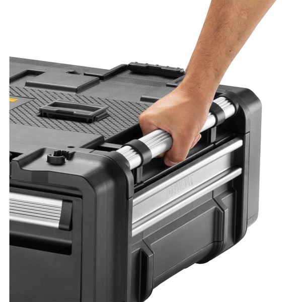 Eine Hand greift den robusten seitlichen Metalltragegriff einer DeWalt Werkzeugbox.