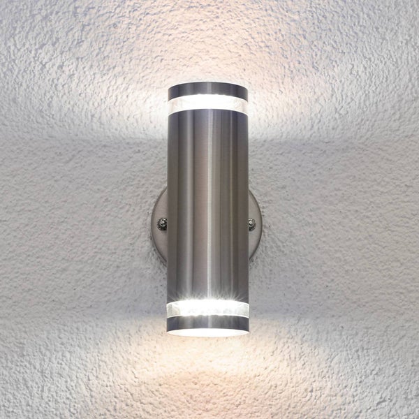 Zylindrische Außenwandleuchte aus Edelstahl mit Lichtaustritt nach oben und unten auf einer strukturierten Wand.