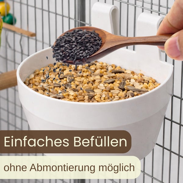 Futternapf für Vögel wird mit einem Löffel Samen befüllt