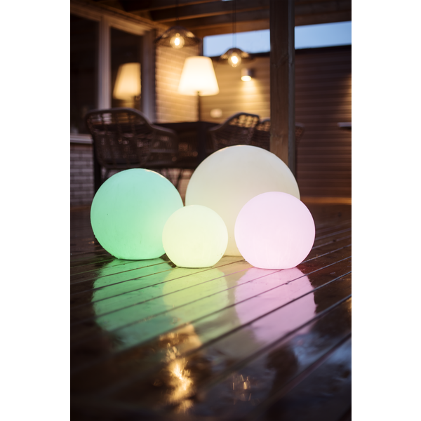 Vier leuchtende Kugellampen unterschiedlicher Größe auf einer Terrasse