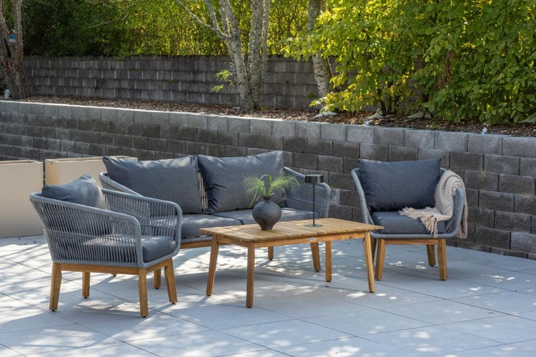 Modernes Garten-Lounge-Set aus grauem Seilgeflecht mit Holzbeinen, bestehend aus Sofa, zwei Sesseln und Couchtisch auf einer Terrasse.