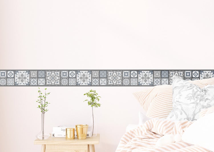Selbstklebende Wandbordüre mit ornamentalem Fliesenmuster in einem hellen Schlafzimmer über einem Bett.