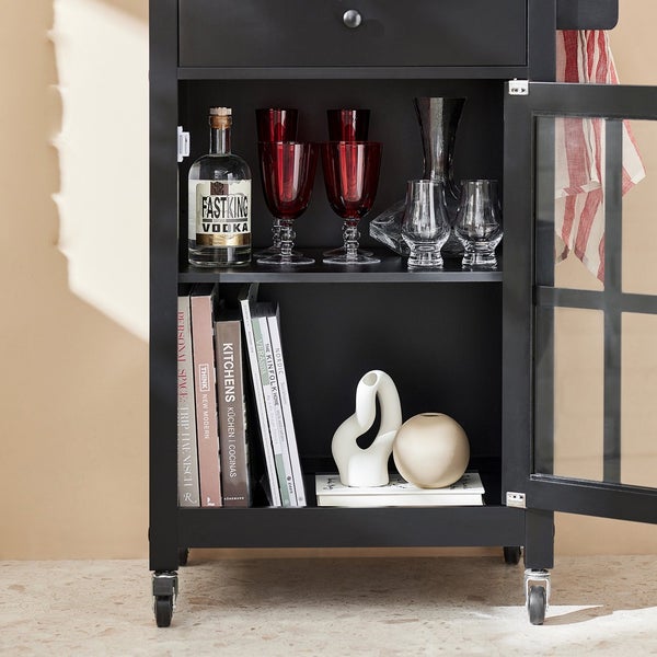 Schwarzer Küchenwagen mit Schublade, Tür mit Glaseinsatz, Geschirr und Dekoration