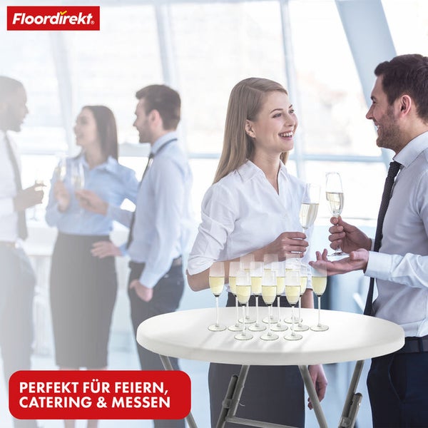 Floordirekt Logo. Ein runder Stehtisch mit Sektgläsern bei einer Veranstaltung in einem hellen, modernen Innenraum.