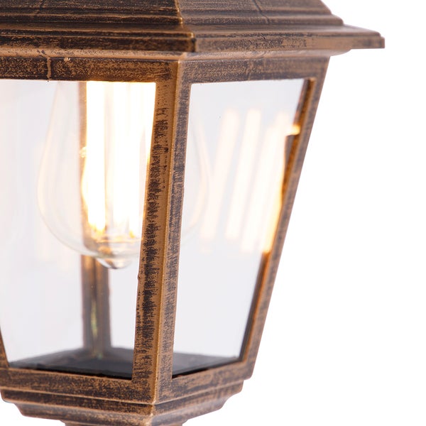 Nahaufnahme einer klassischen Außenlaterne aus Metall und Glas mit einem leuchtenden Filament-Leuchtmittel.