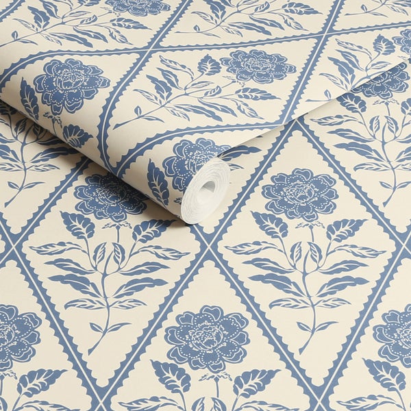 Vliestapete mit floralem Rautenmuster und blauem Blumenmotiv auf hellem Hintergrund, teilweise geöffnete Tapetenrolle.