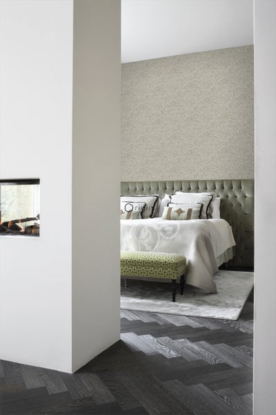 Schlafzimmer mit Bett, gepolstertem Kopfteil, gemusterter Tapete und Bank