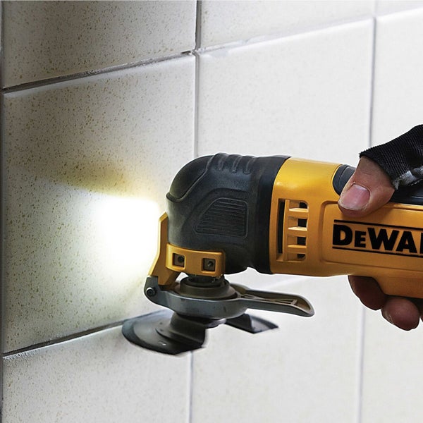 DeWalt Multifunktionswerkzeug mit integrierter Beleuchtung beim Entfernen von Fugenmaterial zwischen Wandfliesen.