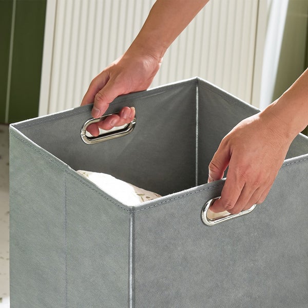 Person hält grauen Stoffkorb mit Metallgriffen