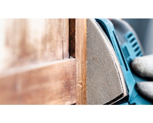 Eine Holzoberfläche wird mit einem Schwingschleifer bearbeitet.