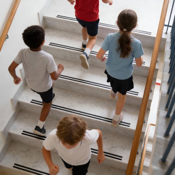 Kinder rennen auf einer Treppe aus hellem Stein mit rutschfesten Trittstufenprofilen nach oben.