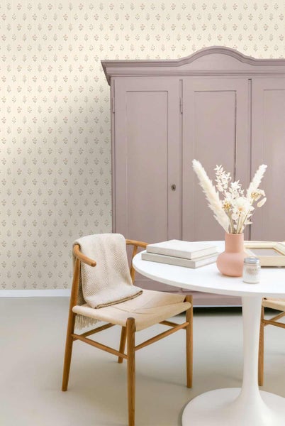 Hell gestalteter Raum mit floral gemusterter Tapete, einem klassischen Kleiderschrank, einem runden Tisch und einem Holzstuhl mit Decke.