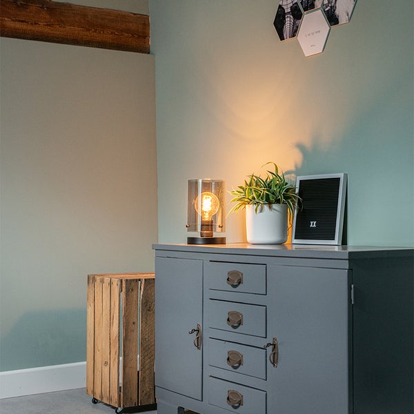 Innenraum mit Tischleuchte, Topfpflanze, Buchstabentafel und Holzschrank