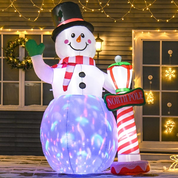 Aufblasbarer Weihnachts-Schneemann mit LED-Beleuchtung, Zylinder, Schal und Nordpol-Schild vor einem dekorierten Haus.