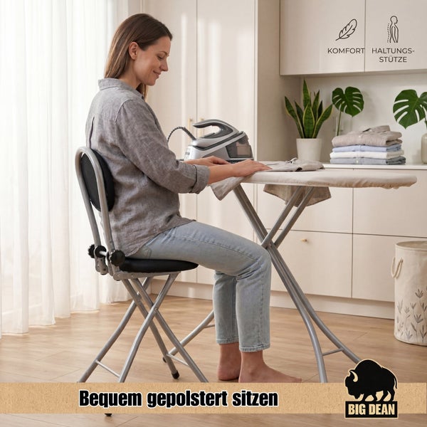 Eine Frau sitzt entspannt auf einem gepolsterten Bügelstuhl vor einem Bügelbrett in einer hellen Wohnküche, Big Dean Logo.