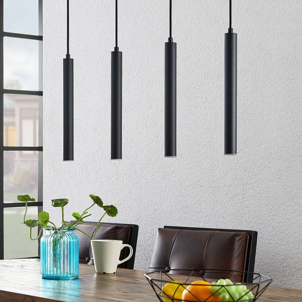 Vier moderne, schwarze zylindrische Pendelleuchten aus Metall über einem Holztisch mit braunen Lederstühlen in einem hellen Essbereich.