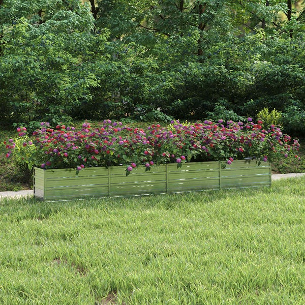 Langes Hochbeet aus verzinktem Stahl mit rosa und violetten Blumen auf einem Rasen vor grünen Sträuchern.